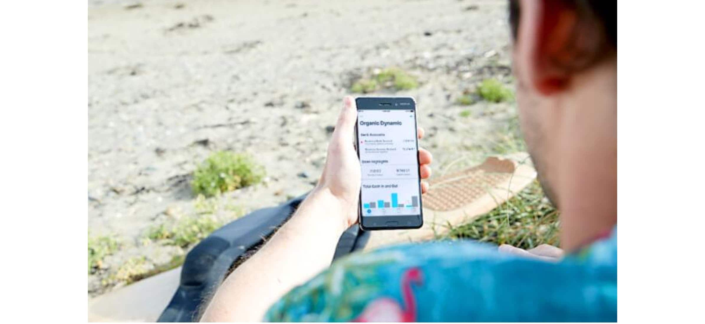 Jack looking at his Xero accounts on his phone, as seen from over his shoulder.